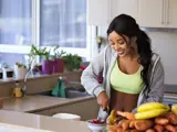 Vrouw snijdt fruit in de keuken.