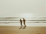 Twee mensen rennen samen op het strand.